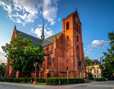 Historic red brick church with clock tower on sunny day.
