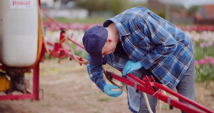 Farmer repairing red agricultural machinery in a field