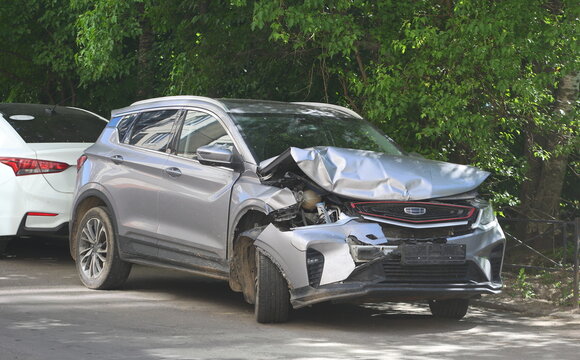 A broken-down gray Chinese crossover is parked under the trees, Bolshevik Avenue, Saint Petersburg, Russia, June 07, 2026