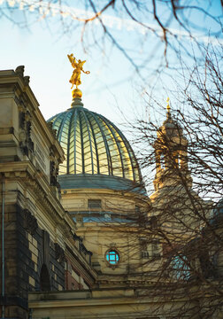 DRESDEN, GERMANY - OCTOBER 2025: The glass ribbed dome of the historic Kunstakademie framed by tree branches in warm sunlight