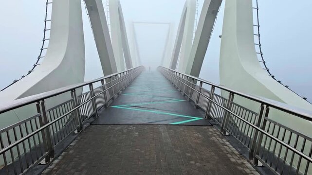 Symmetrical wide shot of modern pedestrian wave bridge disappearing into thick fog horizontal view. Kyiv, Ukraine Wave bridge