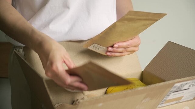 Close-up shot of a person opening a cardboard package and taking out contents horizontal view