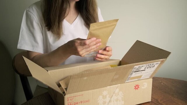 Close-up shot of a person opening a cardboard package and taking out contents horizontal view