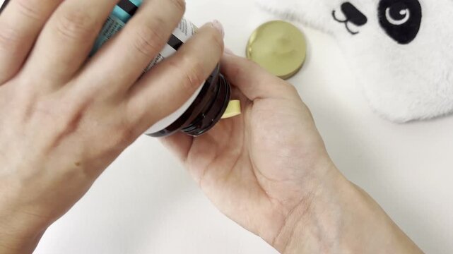 Woman pouring vitamin b complex supplement pills from a bottle into her palm before bed for insomnia and stress relief, taking medicine isolated on a white background
