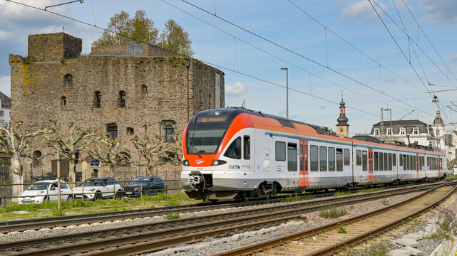 R&uuml;desheim am Rhein, Germany - 17 April 2026:  VIAS Rail electric multiple unit EMU train passing one of Rudesheim's historic buildings as it approaches the railway station
