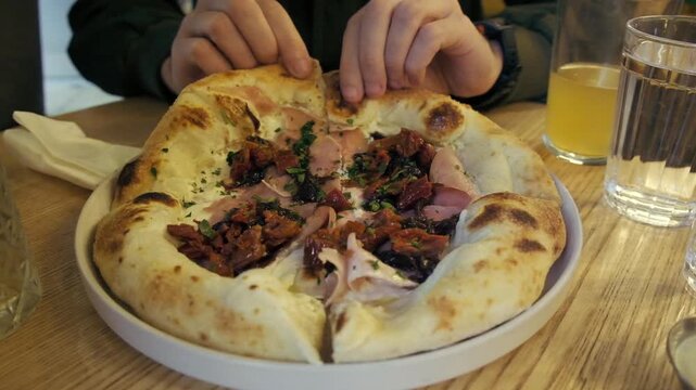 Close-up shot of a man taking a bite of a slice of pizza in a cafe horizontal view