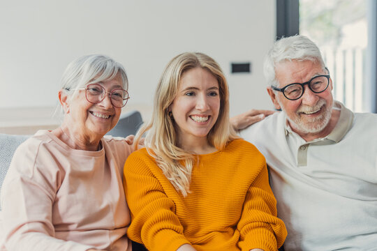 Happy multi-generational family portrait featuring an elderly couple and a young adult woman sharing a warm moment, embracing happiness and the bond between generations at home