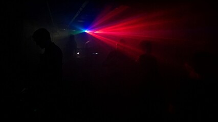Naklejka premium Dark underground club with single colorful laser beam through haze.