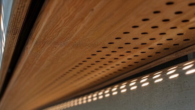 Extreme close-up of wooden soffit with sunlight streaming through holes.