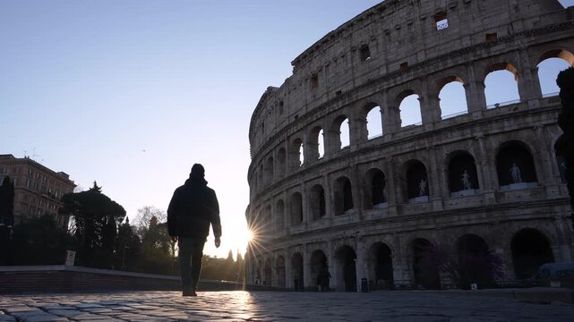 Rome, Italy - March 18, 2026: Roman Colosseum at Sunrise Beautiful Start Burst Lens flare. A Male Photographer Walks Through Frame Towards Flare