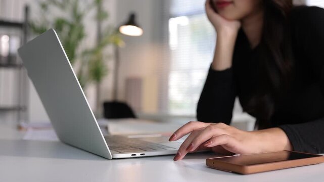 Unmotivated female employee wasting time at her modern office desk.