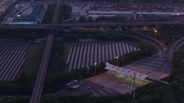 Aerial photography of a photovoltaic power station near an urban transportation hub at sunset