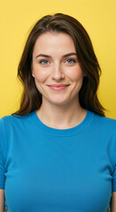 Fototapeta premium Close up portrait of a smiling young woman against a yellow background. Happy female with blue eyes wearing a blue t-shirt