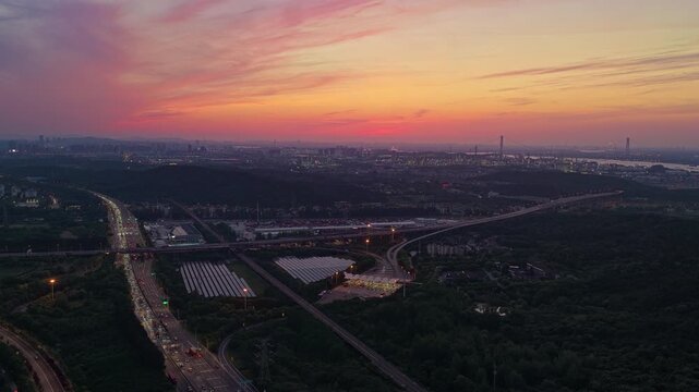 Aerial photography of a photovoltaic power station near an urban transportation hub at sunset