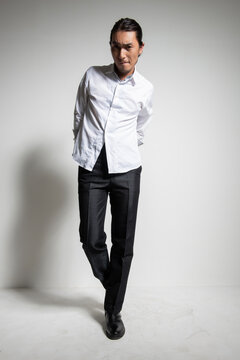 Studio portrait of an Asian man wearing a white shirt.
