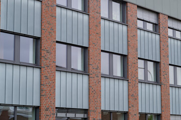 Obraz premium Modern building design with brick and metal panels in urban setting captured during daylight hours