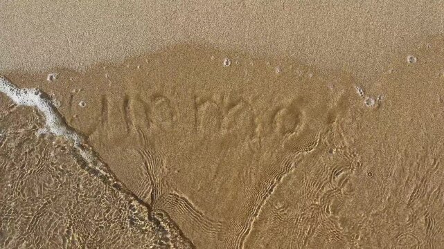 Summer word handwritten on sand washed away by sea wave