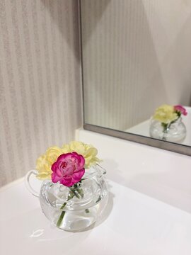 Pink ranunculus yellow rose in glass pot bathroom mirror reflection lifestyle interior