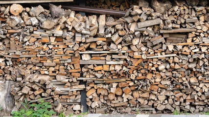 Stacked firewood logs and chopped timber in a shed © Abzal