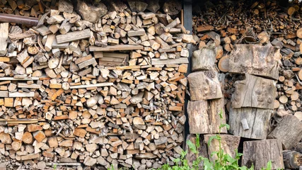 Stacked firewood logs and chopped timber in a shed © Abzal