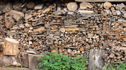 Stacked firewood logs and chopped timber in a shed © Abzal