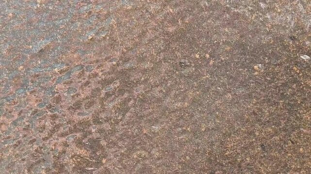 Water overflowing on granite stone wall of swimming pool