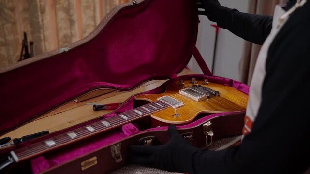 Guitar Technician Opening Electric Guitar Case for Inspection and Service
