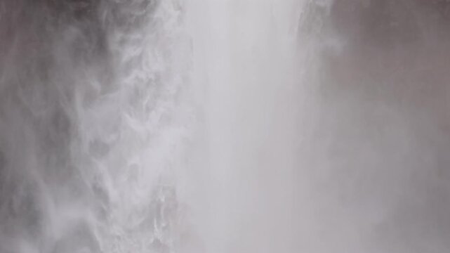Majestic aerial view of the Hengifoss waterfall in East Iceland. Powerful water plunging down basalt strata with distinctive red clay layers