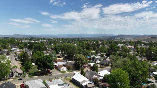 Low aerial above small town Baker City Oregon in spring with blue sky