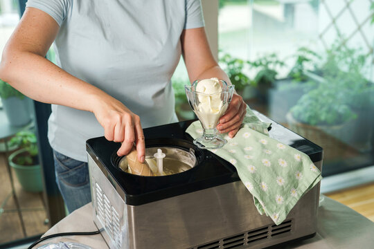 Making homemade ice cream in an ice cream machine. Fresh frozen dessert being prepared in a home kitchen