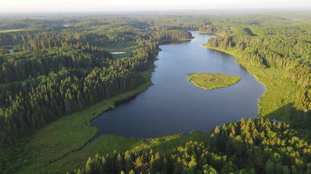 Aerial view while flying over small lakes surrounded by a green northern forest in a national park

