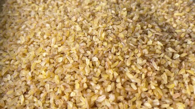 Raw bulgur wheat groats falling down. Horizontal