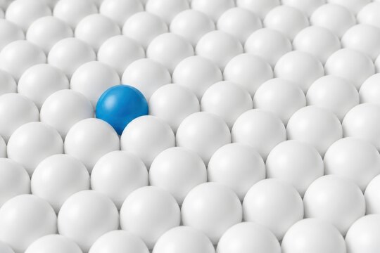Blue sphere standing out from white spheres in a crowd concept for uniqueness leadership and choice