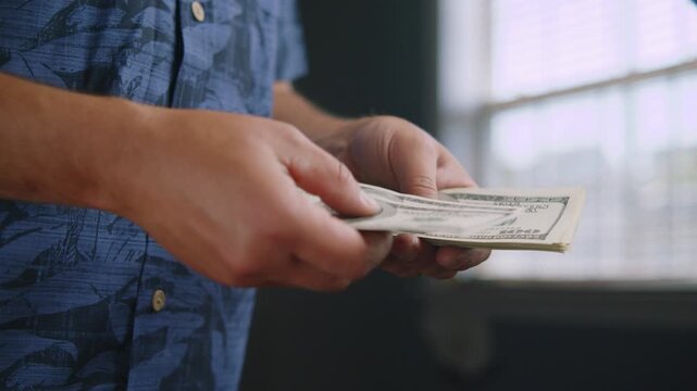 Hands gently sift through crisp banknotes in a sunlit room, highlighting the importance of budgeting and thoughtful spending during daily routines