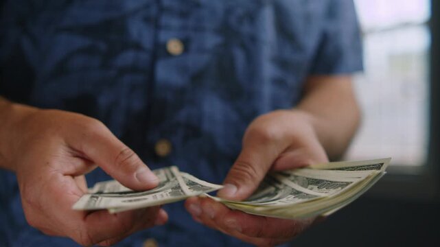 Hands skillfully count folded bills in a warm room, highlighting the textures and colors of currency. Each movement reveals a careful process of handling cash