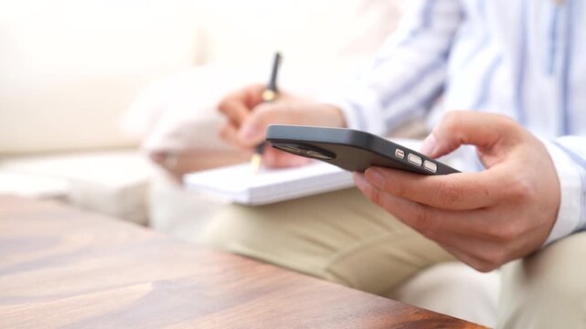 Using smartphone while taking notes for task management, workflow tracking and online communication. Digital productivity, business planning, information management and paperless work process concept