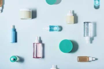 Skincare products, serums and creams artfully arranged on a light blue background, creating a beauty flat lay © colnihko