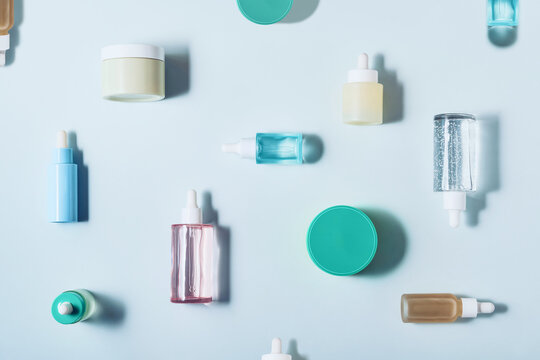 Skincare products, serums and creams artfully arranged on a light blue background, creating a beauty flat lay