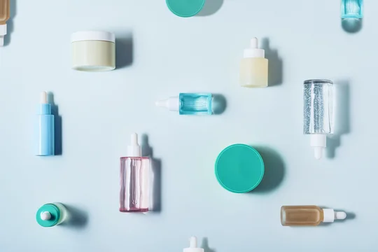 Skincare products, serums and creams artfully arranged on a light blue background, creating a beauty flat lay