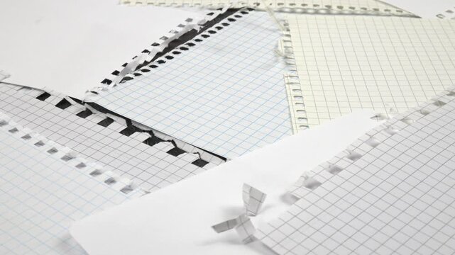 Sheets torn from various spring-bound notebooks lie on a table, background