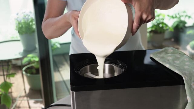Pouring creamy ice cream base into ice cream maker. Homemade frozen dessert preparation process