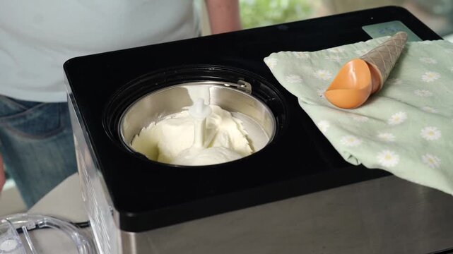 Fresh homemade ice cream churning in ice cream machine. Frozen dessert preparation and food production process