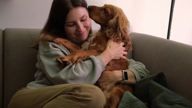 Smiling woman hugging her affectionate cocker spaniel dog on couch