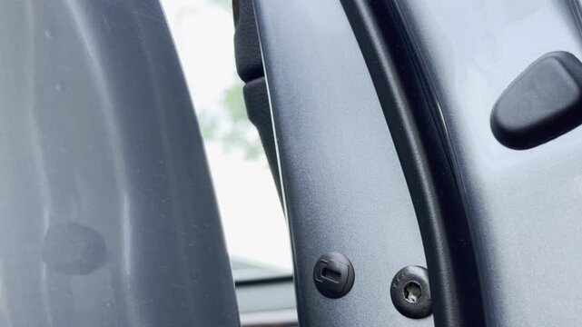 A hand pulls a grey car door open outdoors. The mechanical latch releases. This creates a sharp clicking and slamming sound.