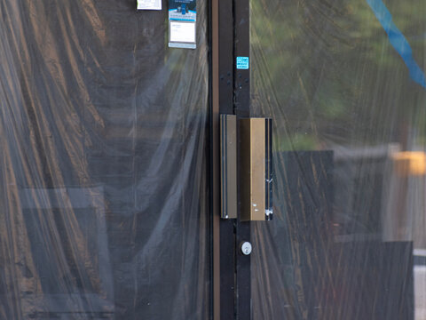 Double glass doors with black plastic hiding the remodeling of the business. 
