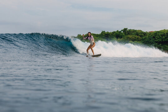 Surfer woman rides on wave on surfboard in ocean, aquatic sport