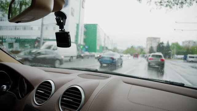 Interior view from a moving vehicle with windshield wipers clearing rainwater from the glass