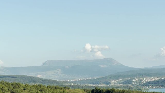 A majestic mountain towers over a lush valley and reservoir. The breathtaking view inspires total tranquility and awe. This grand landscape creates a serene and peaceful feeling.