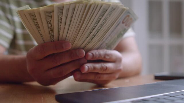 Hands gracefully handle crisp bills in a warm workspace, reflecting moments of focus and anticipation as sunlight filters through the window, creating a serene atmosphere
