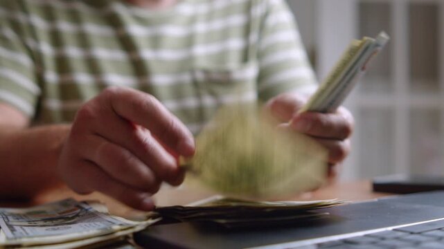 Hands methodically arrange and count bills on a warm wooden desk, surrounded by a welcoming atmosphere. Each movement shows focus and intent while handling cash
